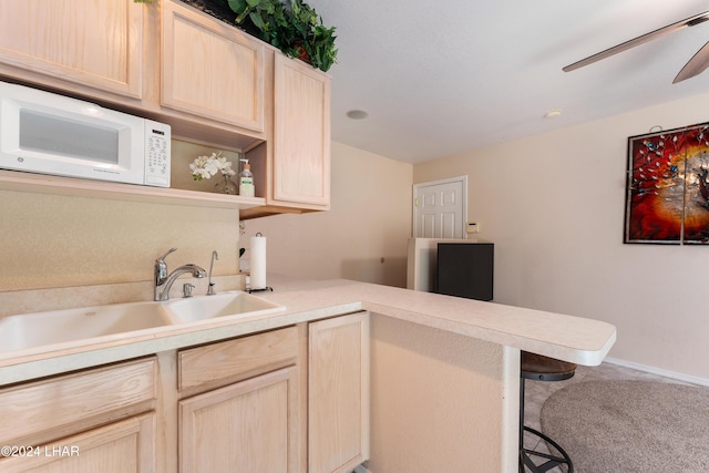 kitchen featuring sink, light brown cabinets, a kitchen bar, and kitchen peninsula