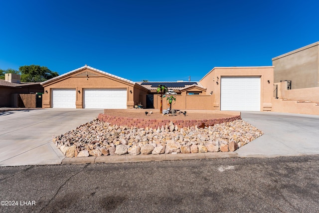 ranch-style home featuring solar panels, a tiled roof, stucco siding, a garage, and driveway