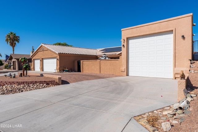 view of front of property featuring stucco siding, a tile roof, and a garage