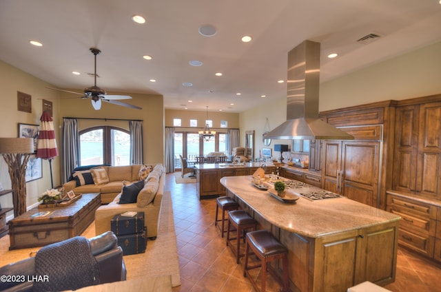 9124 Lakeview Dr, Parker, AZ 85344 - kitchen with tile patterned floors, a kitchen bar, light stone counters, a kitchen island, and island exhaust hood