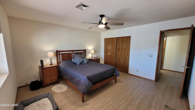 bedroom featuring ceiling fan, a closet, light hardwood / wood-style flooring, and a textured ceiling