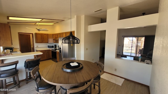 dining room featuring light hardwood / wood-style floors, ceiling fan, and a high ceiling