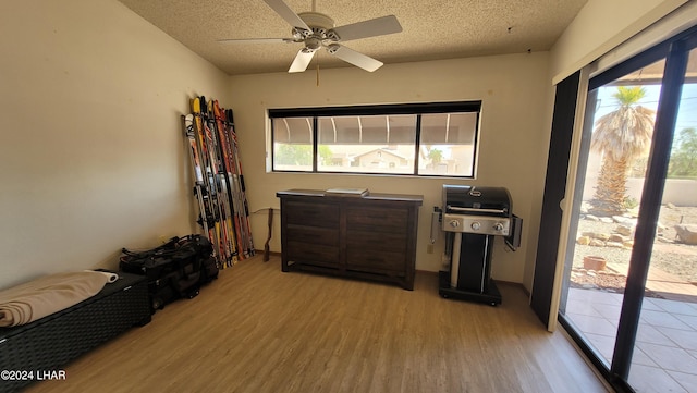 living area featuring ceiling fan, light hardwood / wood-style flooring, and a textured ceiling