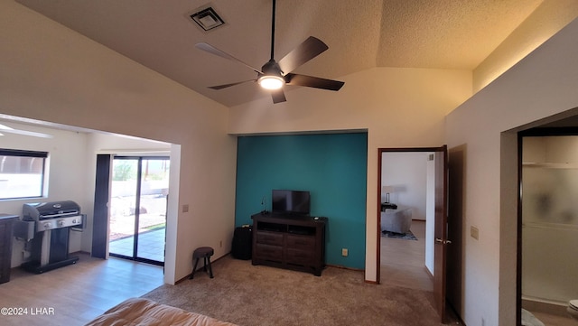 interior space with ceiling fan, lofted ceiling, light carpet, and a textured ceiling