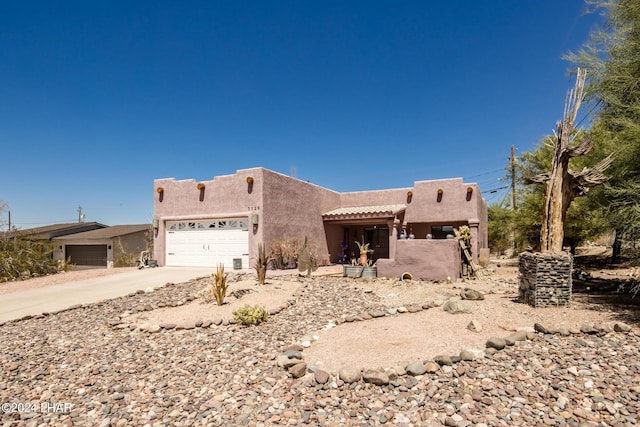 adobe home featuring an attached garage, concrete driveway, and stucco siding