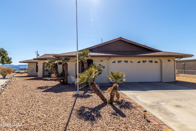 ranch-style home with a garage, driveway, and stucco siding