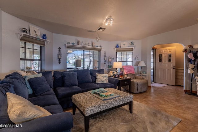 living room featuring arched walkways and visible vents