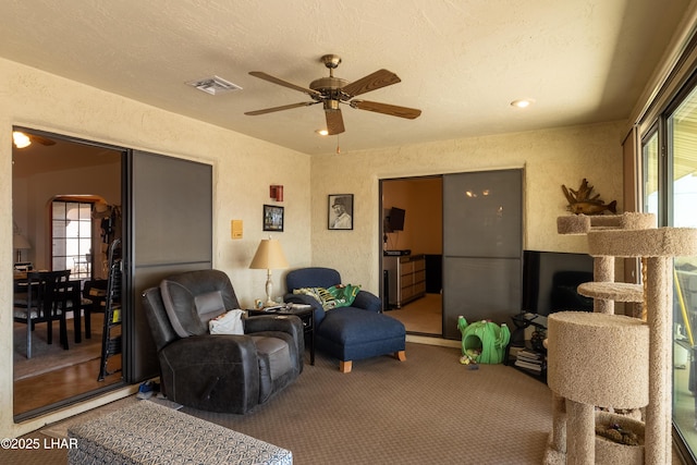 living room with visible vents, plenty of natural light, carpet, and a textured wall