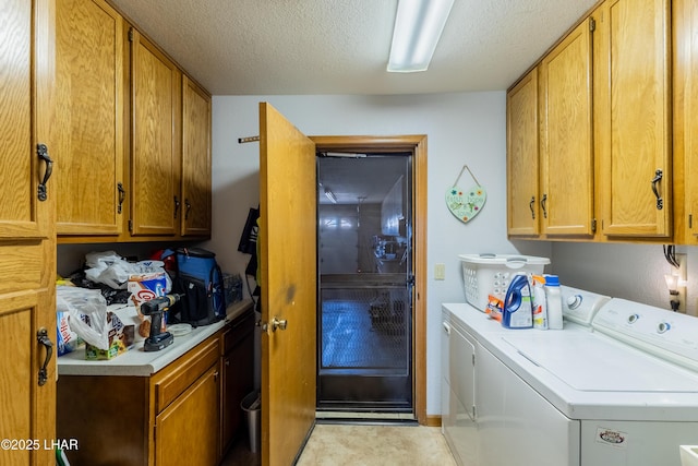 clothes washing area with cabinet space, a textured ceiling, and washing machine and clothes dryer