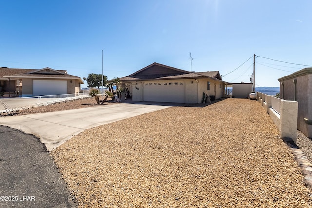 view of front facade featuring fence, a garage, driveway, and stucco siding