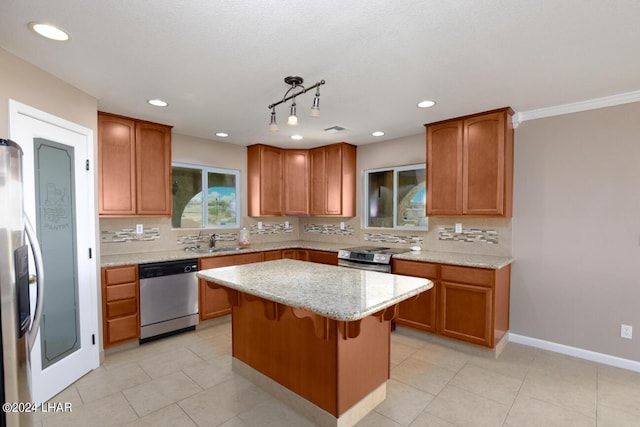 kitchen with light stone counters, appliances with stainless steel finishes, a kitchen island, pendant lighting, and backsplash