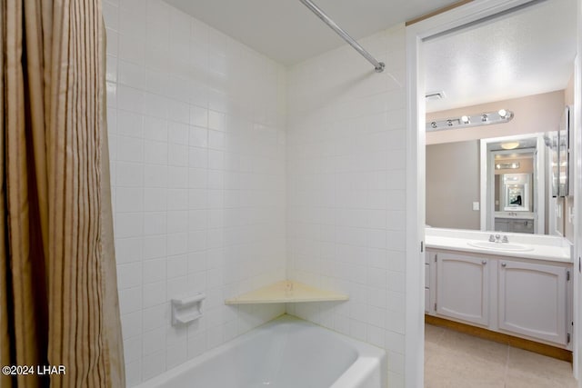 bathroom featuring tiled shower / bath, vanity, and tile patterned flooring