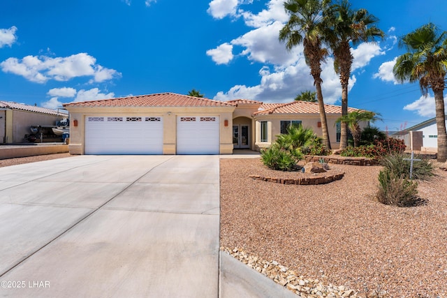 mediterranean / spanish home featuring a tiled roof, an attached garage, stucco siding, and concrete driveway