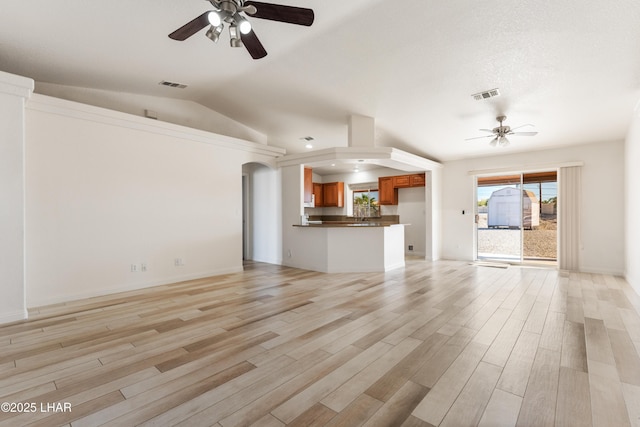 unfurnished living room with ceiling fan, light wood-type flooring, arched walkways, and visible vents