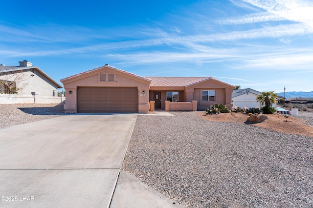 ranch-style house featuring an attached garage, a tiled roof, concrete driveway, and stucco siding