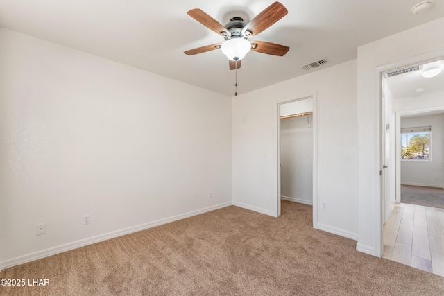 unfurnished bedroom featuring light carpet, baseboards, visible vents, and a walk in closet