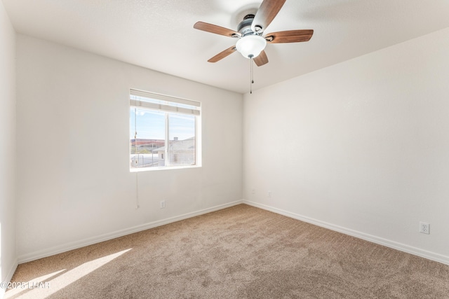 carpeted empty room featuring ceiling fan and baseboards