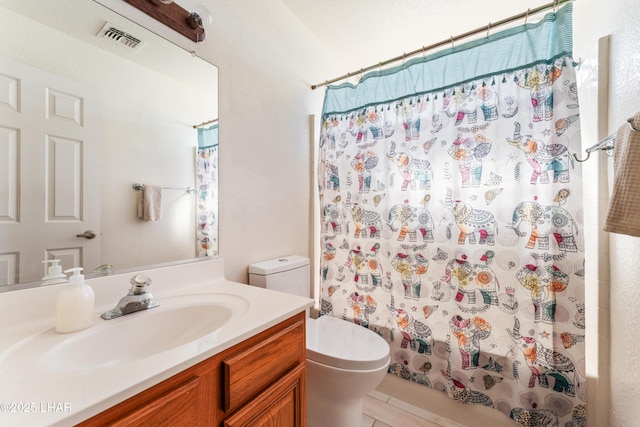 bathroom featuring toilet, vanity, and visible vents