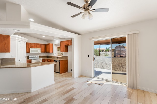 kitchen with light wood-type flooring, white appliances, a peninsula, and a sink