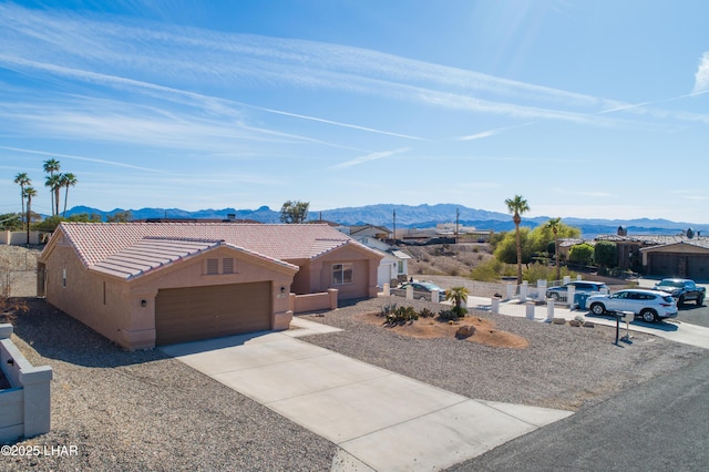 view of front of property with a mountain view, a garage, a tile roof, concrete driveway, and stucco siding