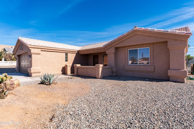 ranch-style home with a garage, a tile roof, and stucco siding