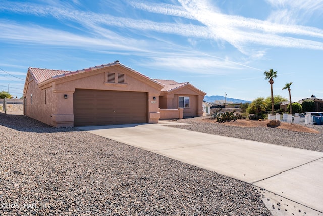 view of front of home with driveway, a tile roof, a garage, and stucco siding