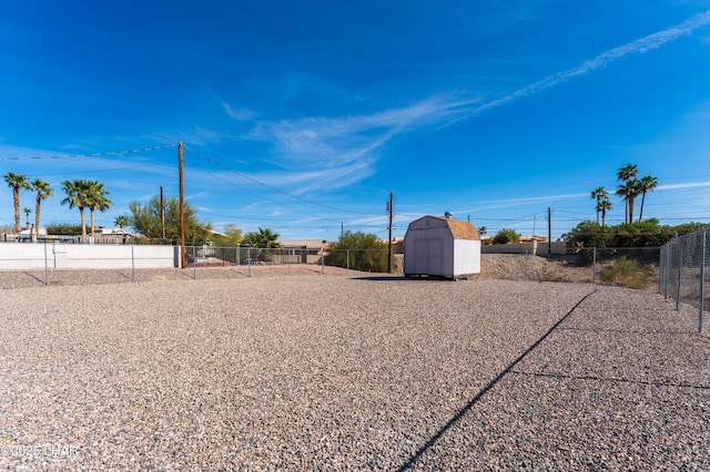 view of yard featuring an outbuilding, a storage unit, and fence