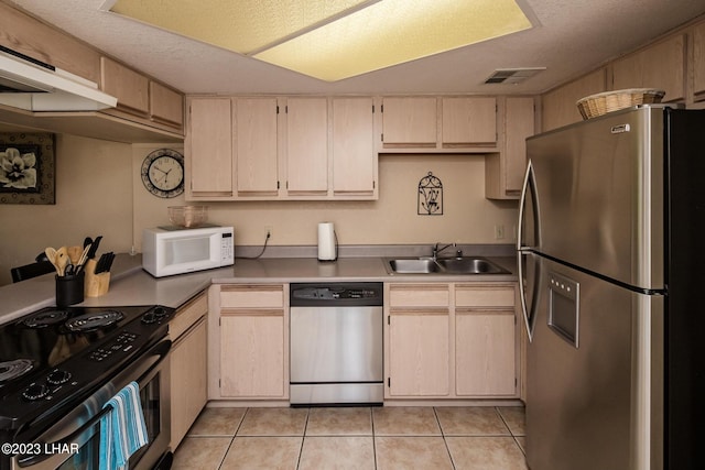 kitchen featuring stainless steel appliances, sink, and light tile patterned floors