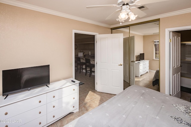 bedroom with crown molding, light tile patterned floors, ceiling fan, and a closet