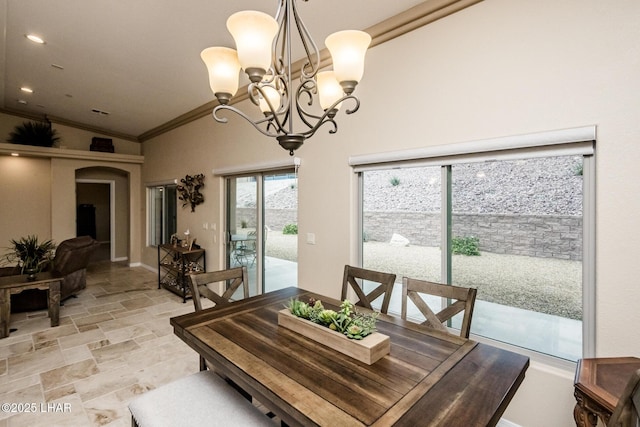 dining space featuring a chandelier, stone finish floor, crown molding, and lofted ceiling