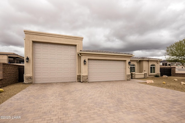 view of front of house with a tile roof, decorative driveway, fence, and a garage