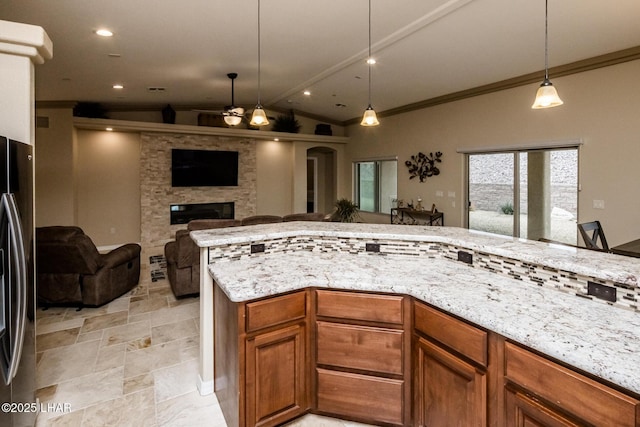 kitchen with stainless steel fridge, light stone counters, open floor plan, and lofted ceiling