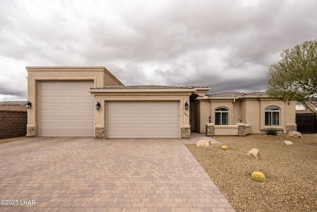 view of front of property with a tile roof, decorative driveway, a garage, and stucco siding