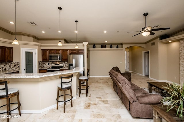 kitchen featuring a kitchen breakfast bar, arched walkways, visible vents, and appliances with stainless steel finishes