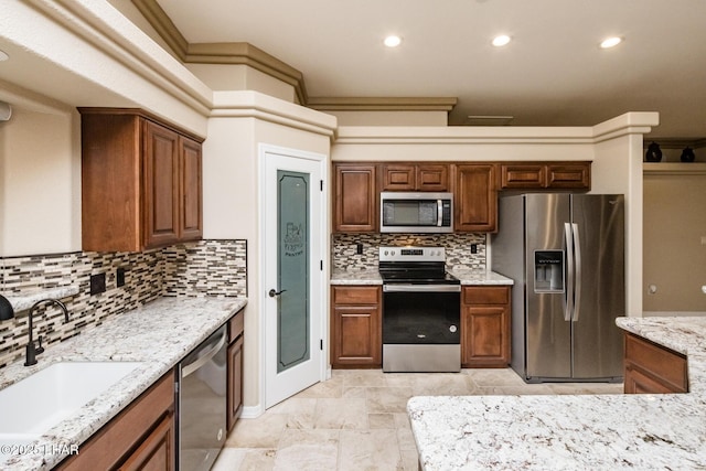 kitchen featuring a sink, decorative backsplash, light stone countertops, and appliances with stainless steel finishes