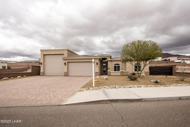 view of front facade featuring fence, an attached garage, stucco siding, a tiled roof, and decorative driveway