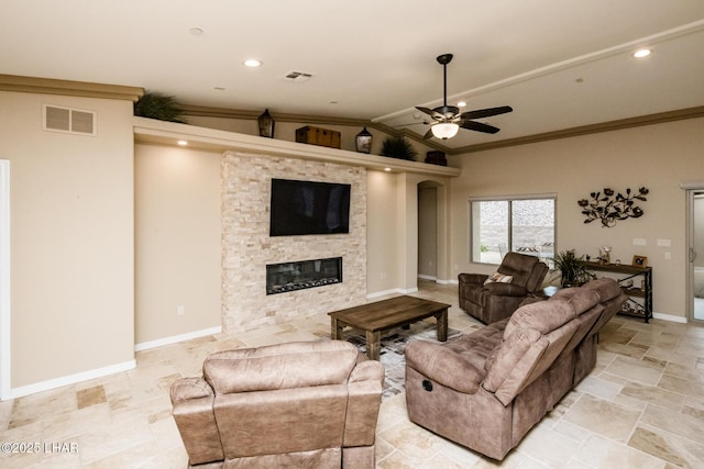 living area featuring baseboards, visible vents, ceiling fan, a stone fireplace, and crown molding