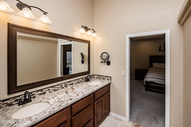 full bathroom featuring double vanity, connected bathroom, baseboards, and a sink