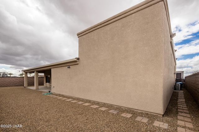 rear view of house with stucco siding, a patio area, and fence