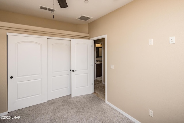 unfurnished bedroom featuring a closet, visible vents, carpet floors, and ceiling fan