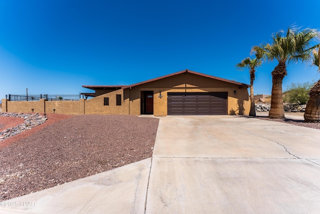 ranch-style home featuring driveway, fence, a garage, and stucco siding