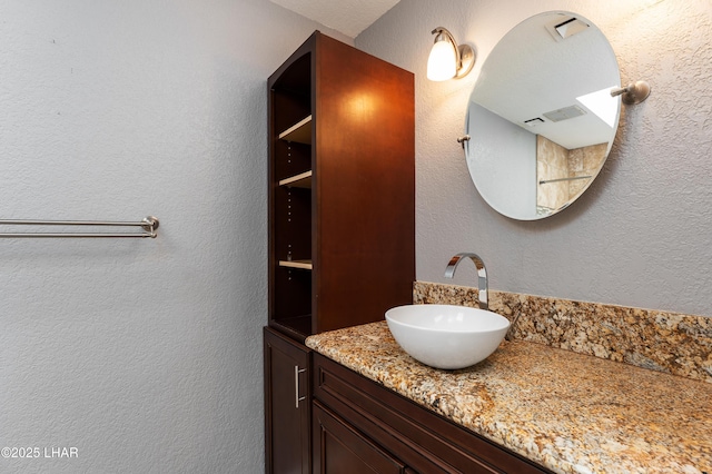 bathroom with a textured wall and vanity
