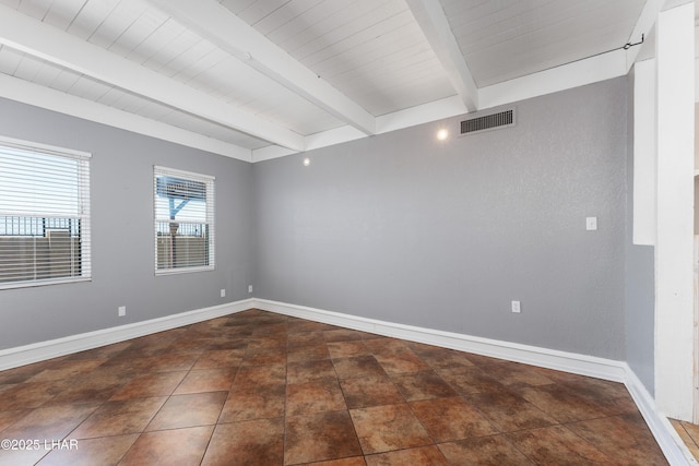 empty room with visible vents, baseboards, and beamed ceiling