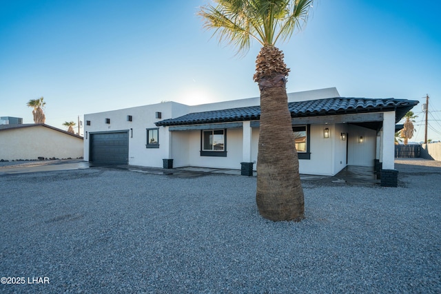 view of front of home featuring a garage, driveway, a tile roof, and stucco siding