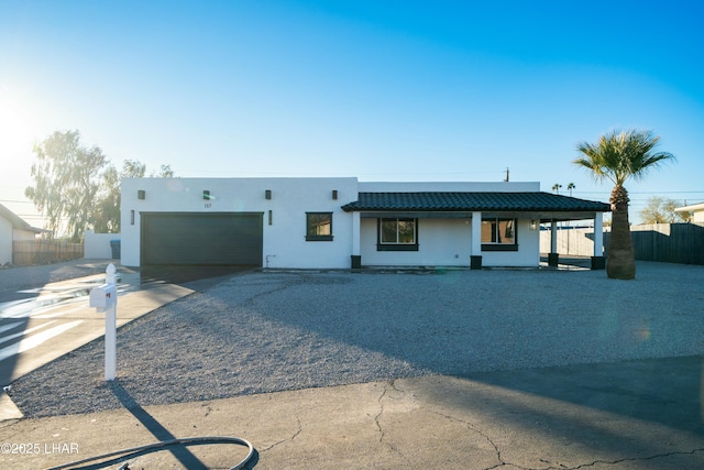 view of front of home featuring driveway, a garage, a tile roof, fence, and stucco siding