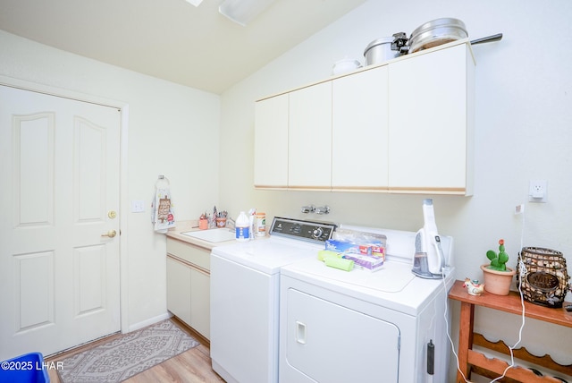 clothes washing area featuring cabinet space, light wood-style flooring, a sink, and independent washer and dryer