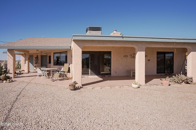 rear view of property with stucco siding, central AC, and a patio