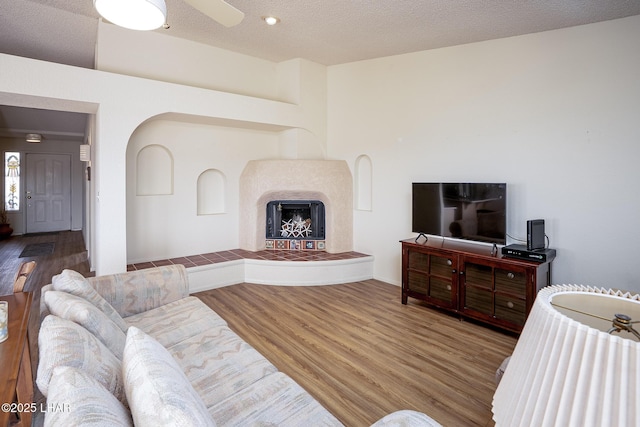 living area with a fireplace with raised hearth, a textured ceiling, and wood finished floors