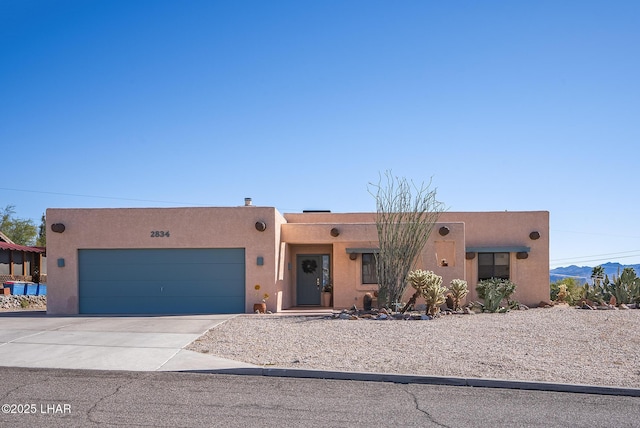 southwest-style home with a garage, concrete driveway, and stucco siding