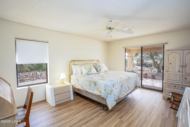 bedroom featuring a textured ceiling, light wood-style flooring, visible vents, a ceiling fan, and access to outside